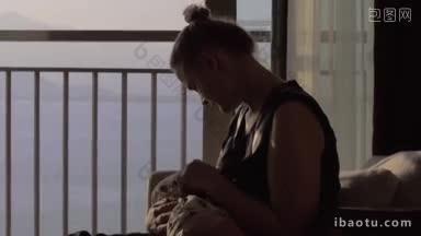 妈妈给宝宝喂奶，女儿坐在扶手椅上，隔着打开的阳台门望着大海，妈妈和孩子